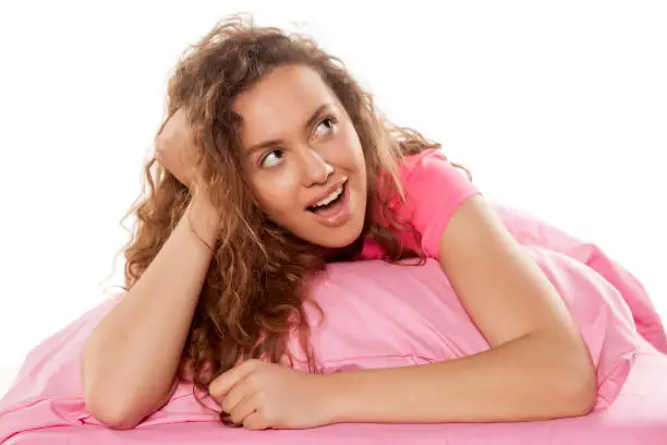 Photo of happy young girl lying on a pillow and thinking