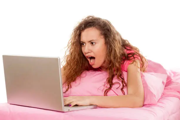 Photo of shocked girl looking at her laptop