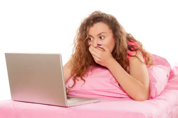 Photo of shocked girl looking at her laptop
