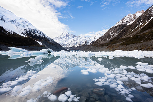 Ice broken off of the Hooker Glacier floats as icebergs in the glacial lake. Mount Cook, New Zealand's highest mountain is reflected in the still waters of the lake.