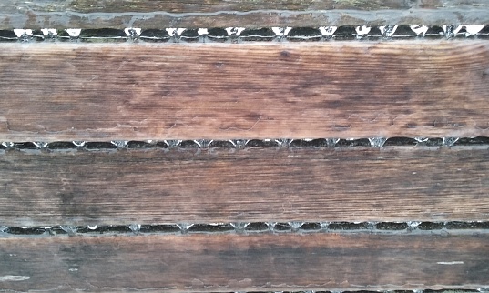 Icicles on the back of a wooden bench in winter.