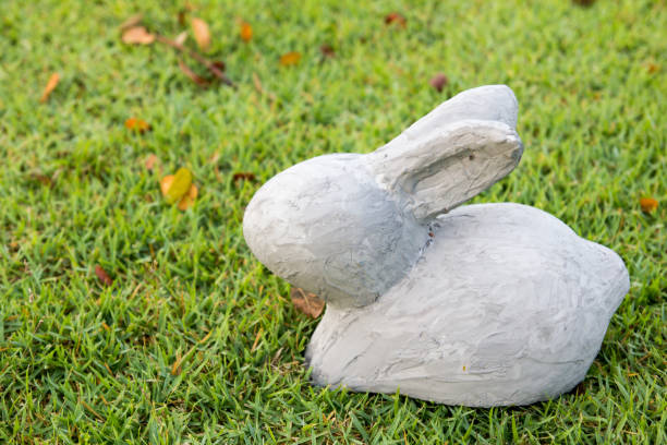 istock White stone rabbit statue on green grass background 639176580