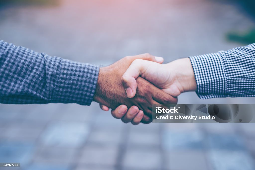 Men shaking hands Men shaking hands. Top view of two men shaking hands while standing on the paving tiles, cement brick floor. Handshake Stock Photo