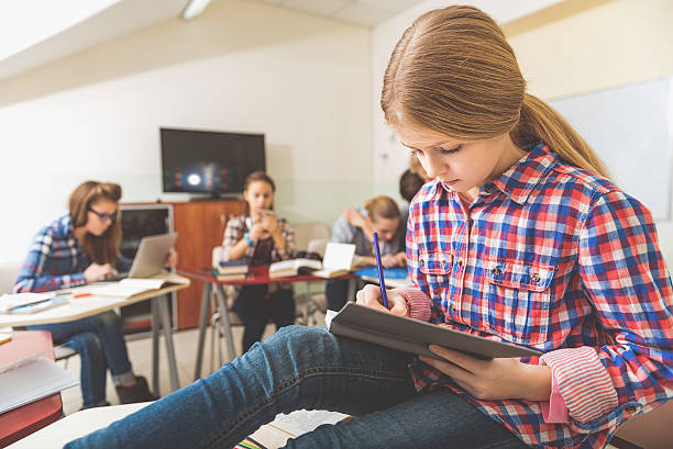 Young female pupil stubbornly writing