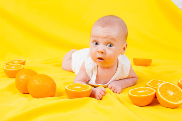 istock baby boy lies on a yellow with oranges 639189018