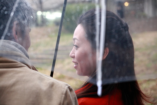 Japanese couple in one umbrella in the rain and staring at each other