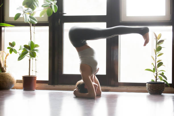 istock Young attractive woman in headstand pose, home interior backgrou 639190068