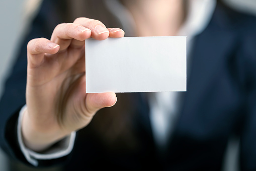 Young women holding a blank business card in hands