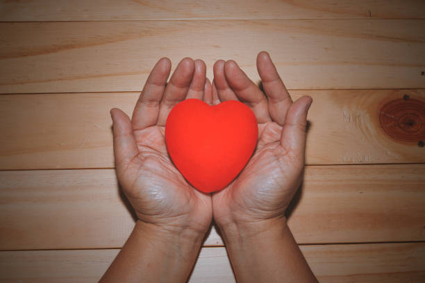 istock Hand holding a red heart on wooden background 639191932