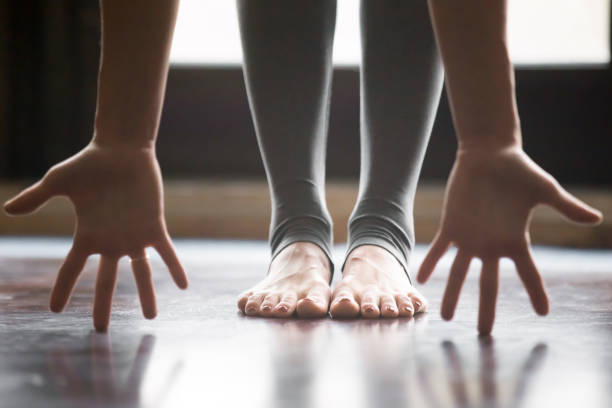 primer plano de la hembra en pose uttanasana, piernas pantalones de yoga - leaning forward fotografías e imágenes de stock