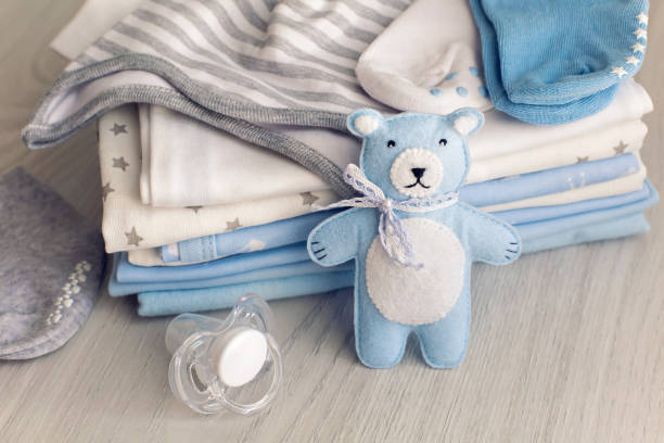 Cute little boy in blue pajamas and pacifier in his mouth standing in crib and looking for mother early in the morning
