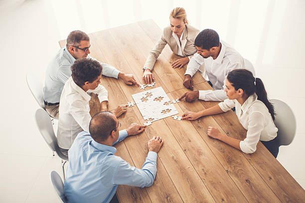 istock Business people putting puzzle pieces together at office 639198270