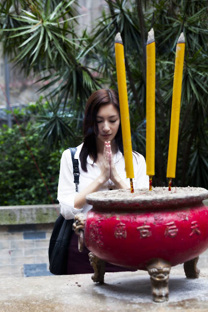 Asian woman praying with incense in Hong Kong