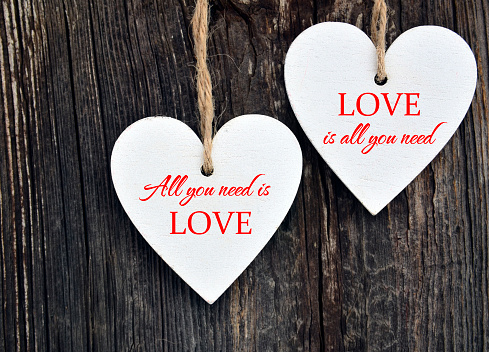 All You Need Is Love.Decorative white wooden hearts on old wooden background.Two Valentine hearts.Valentine's Day or Love concept.Selective focus.