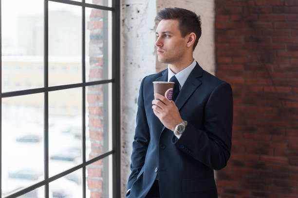istock Businessman drinking coffee in office standing near window. 639210070