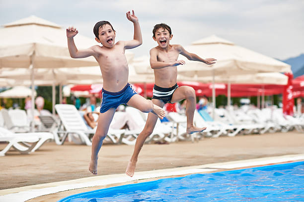 crazy brithers jumping in the swimming pool, making funny face and enjoying the summer day.
