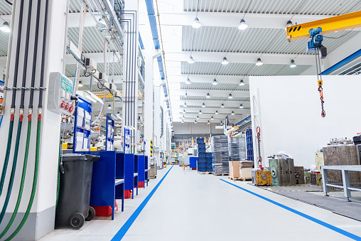 Horizontal image of huge new modern factory with robots and machines producing industrial plastic pieces and equipment. Industrial aisle in factory.