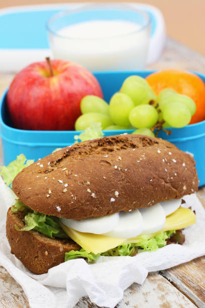 сэндвич с коричневым хлебом с сыром, яйцом вкрутую, фруктами, молоком - lunch bag apple brown стоковые фото и изображения