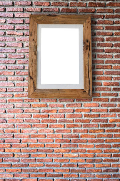 istock Empty wooden picture frame hanging on a brick wall. 639231490