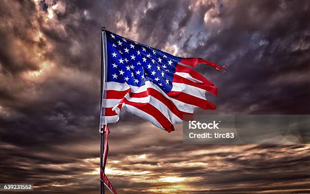 Tattered American Flag Flapping In Ominous Sky Stock Photo - Download Image Now - Torn, American Flag, Run-Down