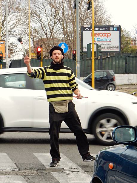 Rome, Lazio, Italy - January 18, 2017: a street juggler while performing at a crossing along the Via Casilina for motorists stop at a red light. After the brief show the young passed between motorists to collect a few coins