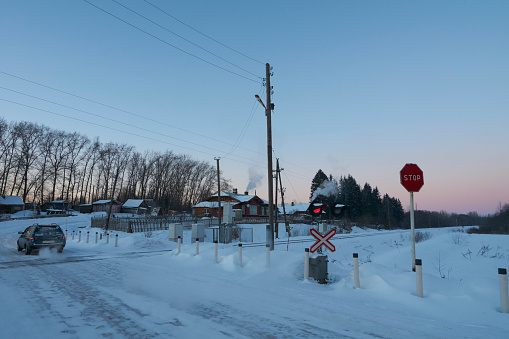 Car crosses railroad at red stop signal. Ostashkovskiy district, Tver oblast, Russia, January 2017.