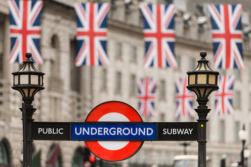 London, United Kingdom - June 12, 2016: British flags and the underground sign late in the day in Piccadilly Circus.