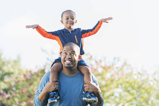 istock Little boy sitting on father's shoulders 639242482