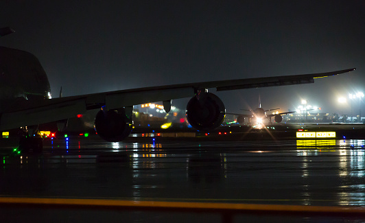 Night at the airport - silhouettes of taxiing airplanes on the runway
