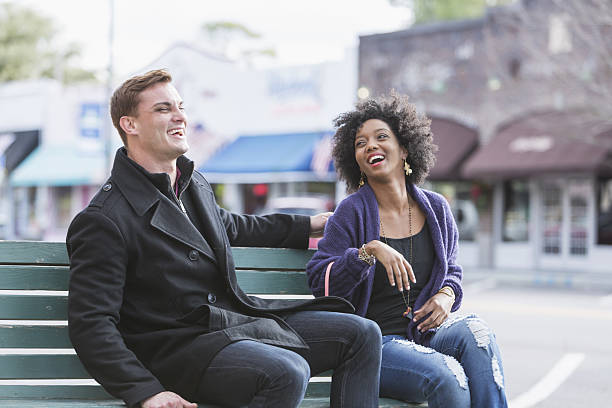 istock Young interracial couple sitting on bench laughing 639246246