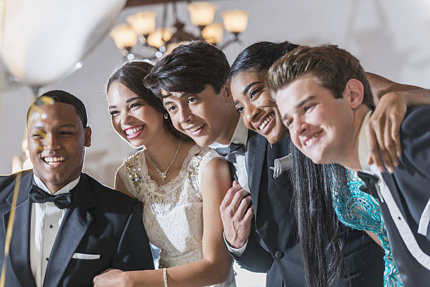 Teenagers and young adults in formalwear A group of five multi-ethnic teenagers and  young adults dressed in formalwear - dresses and tuxedos. They are at a special event, a prom or party at a restaurant. prom photos stock pictures, royalty-free photos & images