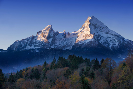 The Watzmann mountain awake in the mornig. Bright blue sky . Fog in the valley. Autumn picture.