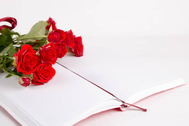 istock Bouquet of red roses with open notebook on white background 639253974