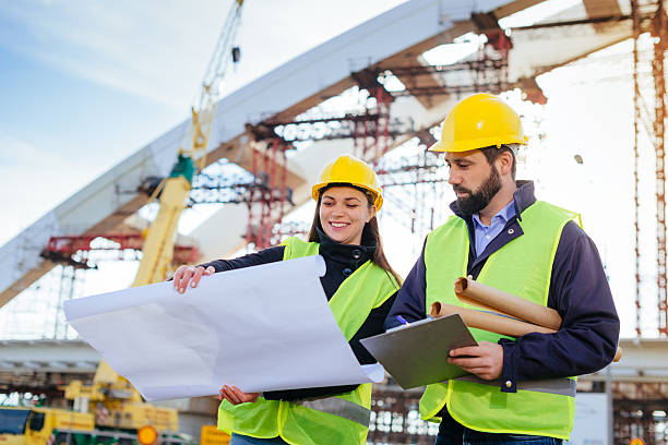 istock Engineers with hardhats and blueprints on construction site 639256000