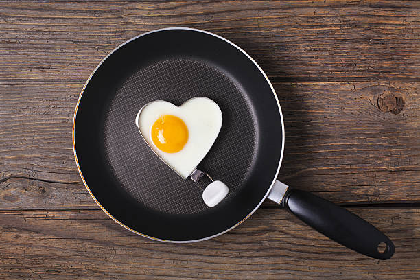 café da manhã dos namorados ovo frito em forma de ferro cultura do coração - eggs breakfast heart shape fried egg - fotografias e filmes do acervo