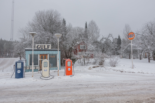 Katrineholm, Sweden - January 19, 2016: Old fashioned gas station, Gulf, in winter, blue station color and blue, white and orange gas pumps.