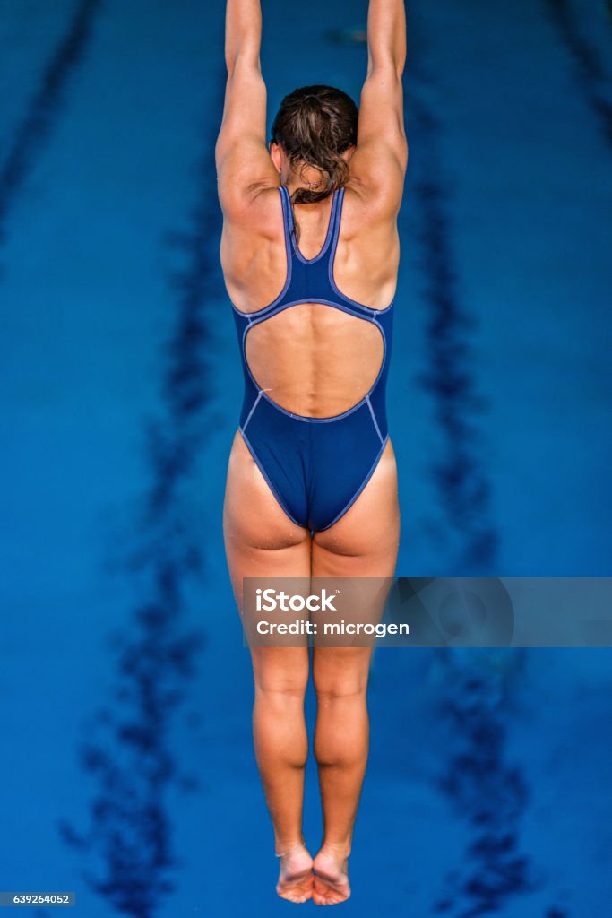 Female springboard diver in the air, high above the pool Diving Into Water Stock Photo