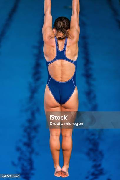 Female Springboard Diver In The Air High Above The Pool Stock Photo - Download Image Now