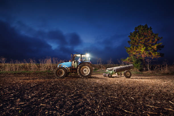 Tractor preparing land with seedbed cultivator at night