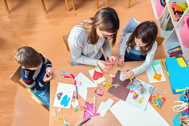 preschool teacher with kids having creative activities - kid painting imagens e fotografias de stock