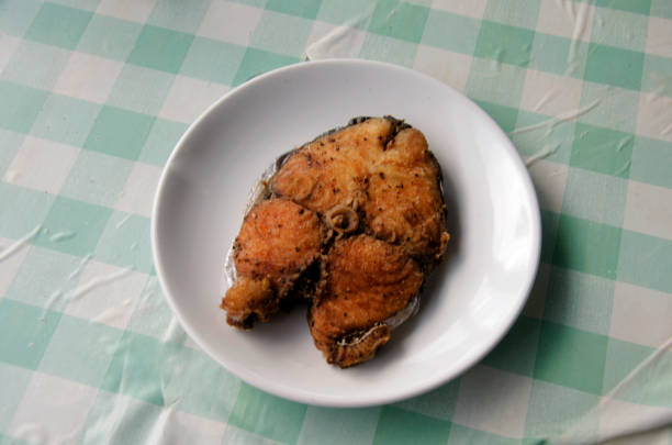 appetizing fried fish fillet with vegetables and herbs on a white plate