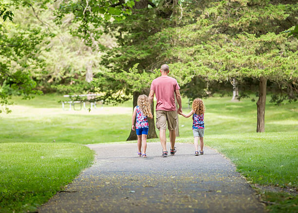 istock Father & Daughters Walking Through Park in Summer 639288188