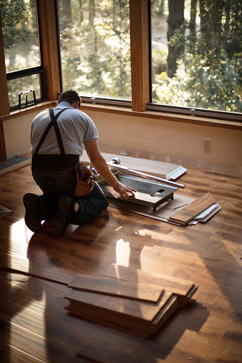 Man installing wood flooring in home.