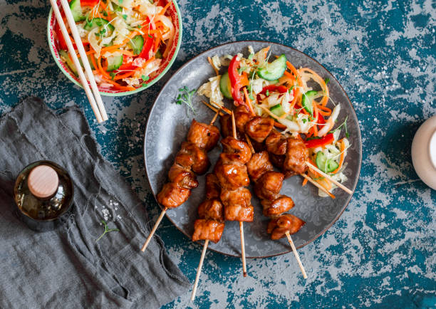 Teriyaki pork skewers and marinated vegetable salad Teriyaki pork skewers and marinated vegetable salad. Asian style lunch, top view chicken skewer stock pictures, royalty-free photos & images