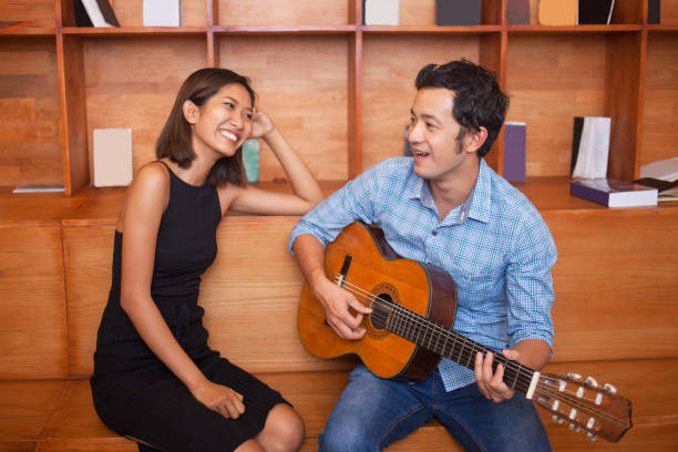 istock Man Singing and Playing Guitar for Smiling Woman 639295362