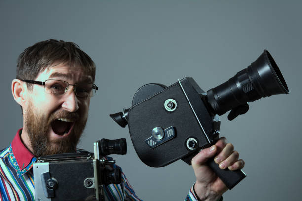 Screaming bearded man two old retro film camera. Man in glasses director cinema operator