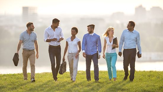 Large group of happy business people walking in nature and talking.