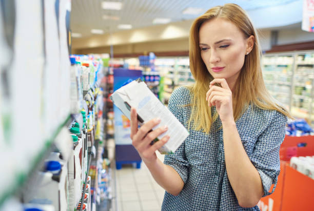 young woman reading label milk - choice thinking women decisions imagens e fotografias de stock