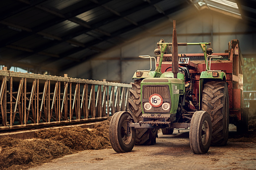 Shot of a rusty old tractor standing in an empty barn