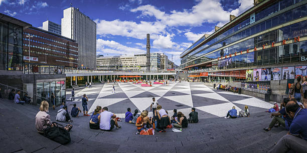 Stockholm crowds of shoppers in Sergels Torg square panorama Sweden Stockholm, Sweden - July 10, 2016: Tourists and locals strolling through the sunlit pedestrian plaza of Sergels Torg beside the Kulturhuset in the heart of Stockholm, Sweden's vibrant capital city. Panoramic image created from five contemporaneous sequential photographs.  stockholm town square sergels torg sweden stock pictures, royalty-free photos & images